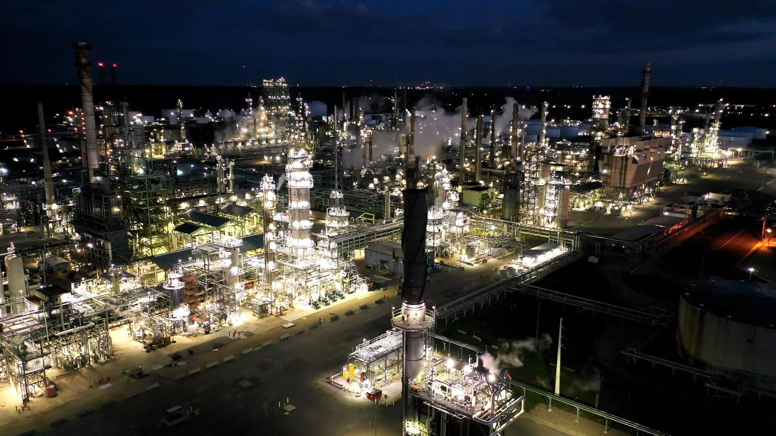 A refinery complex at night seen from the air, its process units picked out in ordered light.
